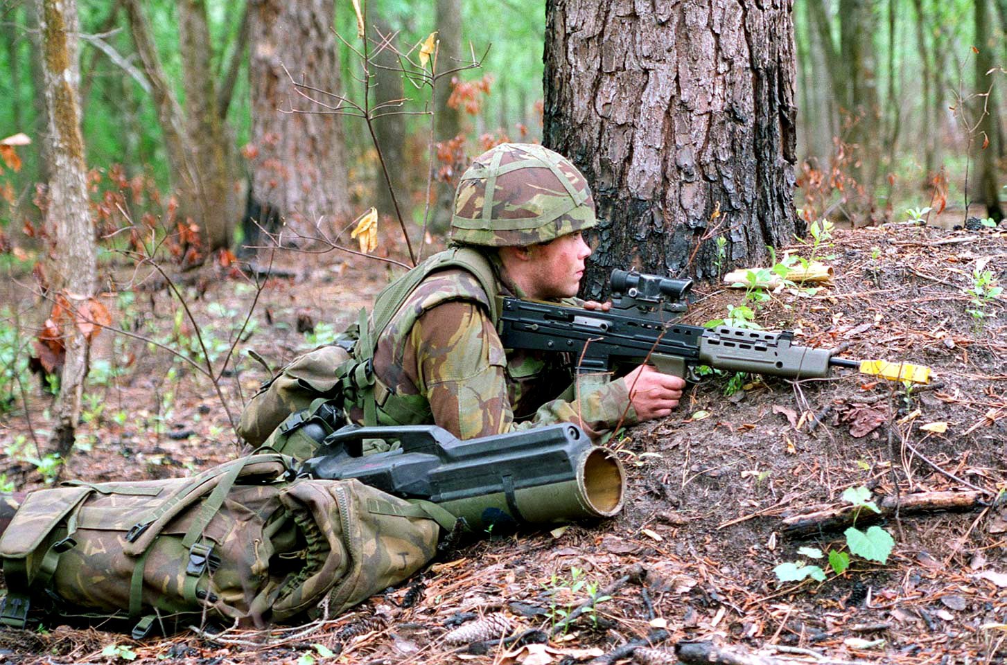 Figure 4 — A British soldier of the 1990s in a wood with an L85A1 fitted with the yellow blank-firing attachment at the muzzle, an anti-tank launcher in its bag beside him. US Marine Corps photograph, public …