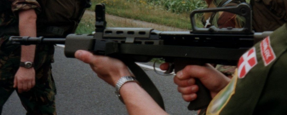 Figure 8 — US Marines and British soldiers at a 1994 NATO cross-training event; a British soldier holds an L85A1 with green furniture while another fires. Photograph by Lklundin, CC BY-SA 4.0, via Wikimedia C…