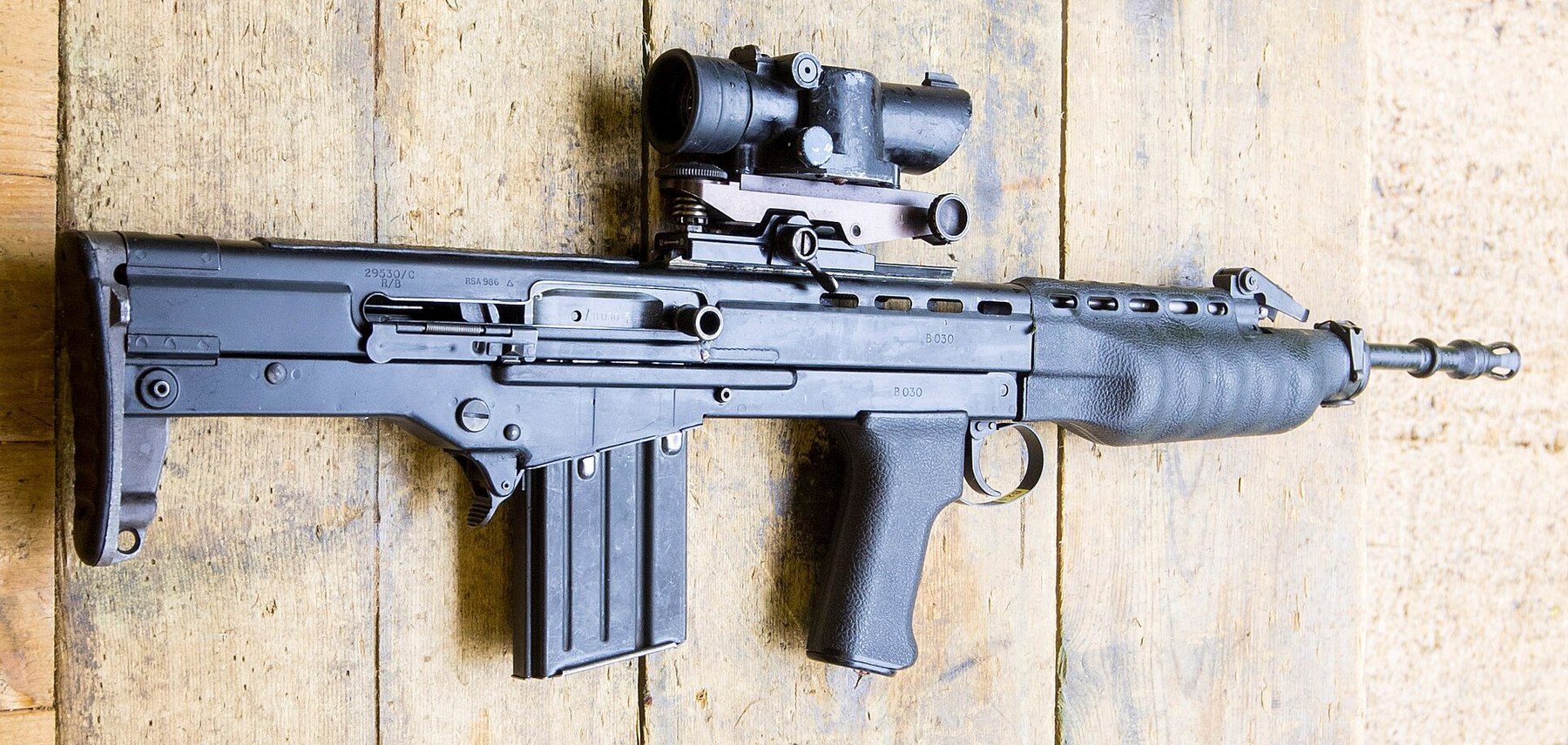 Figure 13 — Detail of the XL64E5 Individual Weapon from the same photograph, with its prototype SUSAT: slimmer than the later rifles, with the paddle magazine catch and a pronounced handguard. Crop by a Common…