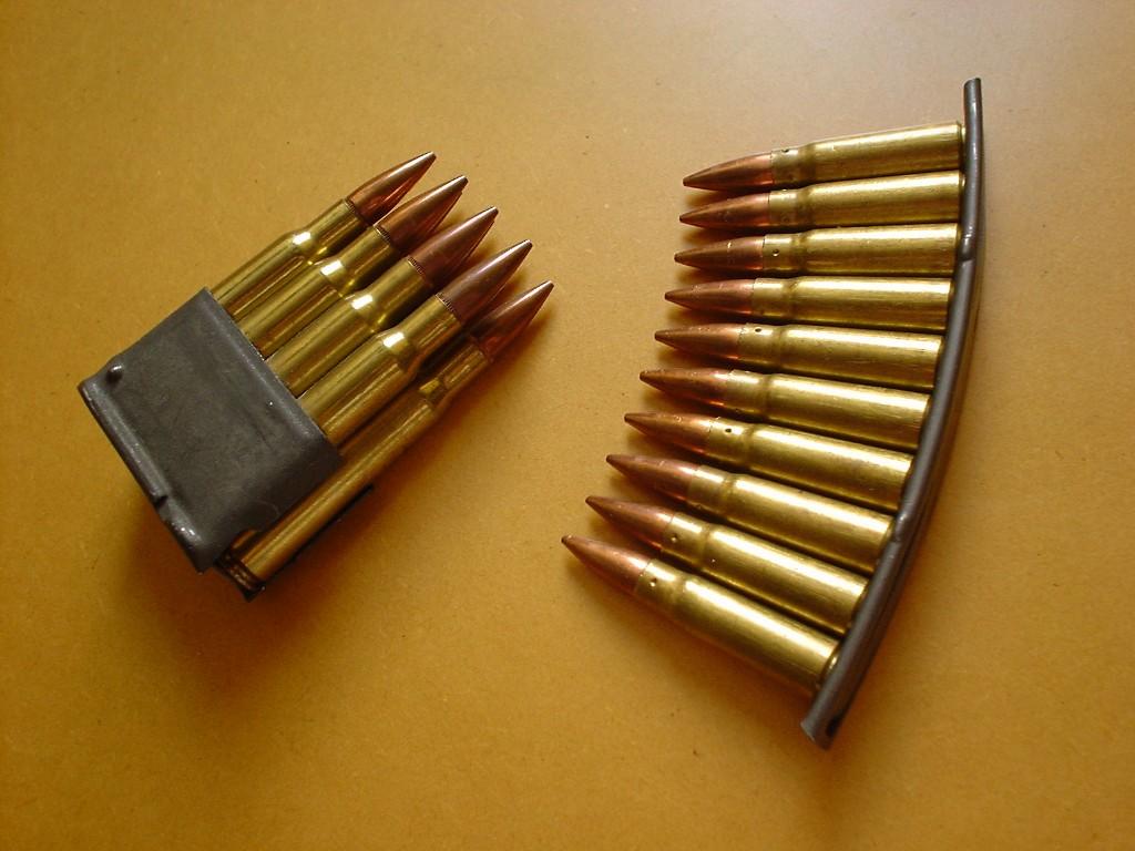 Figure 8 — An M1 Garand en-bloc clip beside SKS ammunition. The Garand's clip goes into the rifle and is ejected by it; the SKS's clip is a loading tool that never enters the magazine and gets reused.