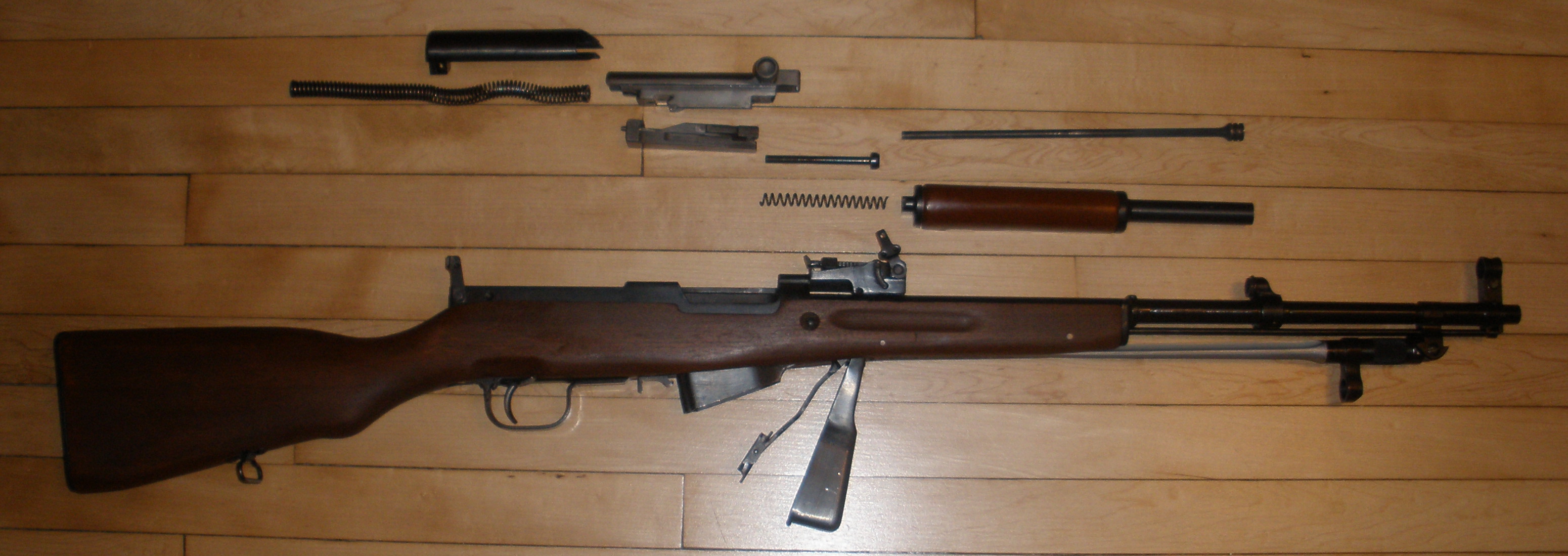 Figure 1 — An SKS field stripped — in this case a Yugoslav M59/66, identifiable by the grenade launcher on the muzzle. Clockwise from top: receiver cover, recoil spring assembly, bolt carrier and bolt, firing…