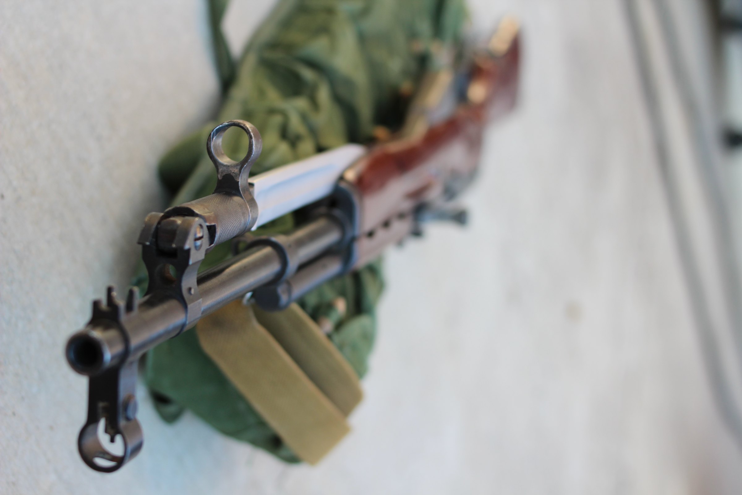 Figure 11 — The muzzle end: hooded front post, gas block, folding bayonet, and the cleaning rod running underneath.