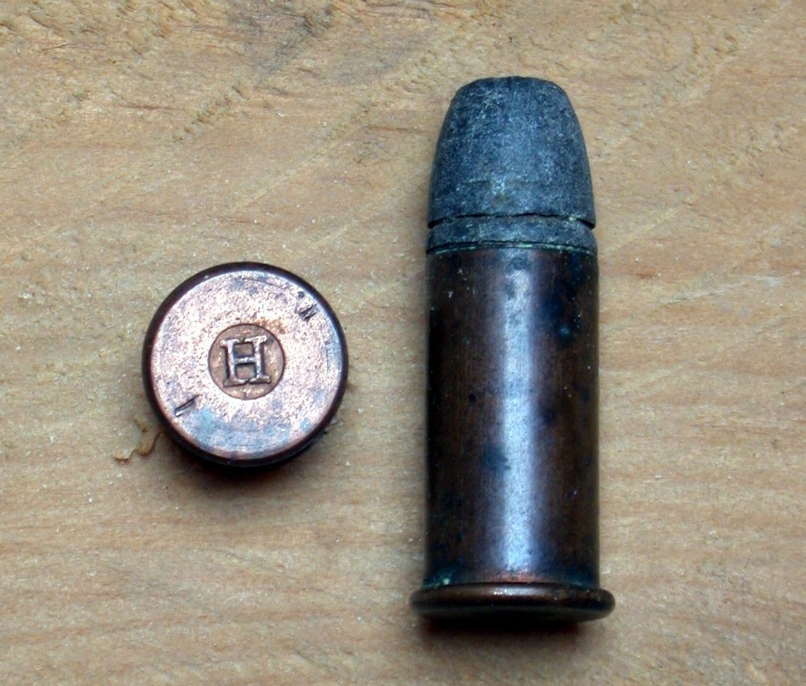 Figure 5 — A .44 Henry flat-nose rimfire cartridge beside its base, stamped with the H that Sawyer says the company adopted as a trademark. Photograph by Hmaag, CC BY-SA 3.0.