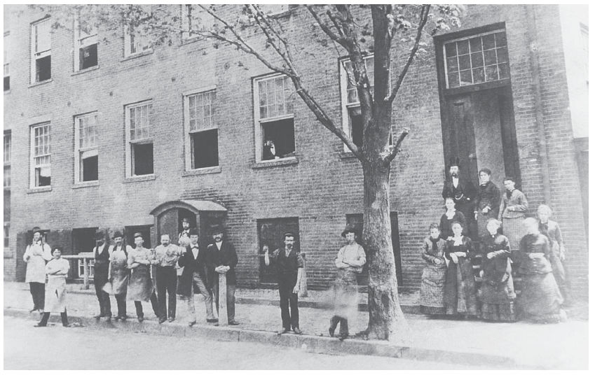Figure 8 — The New Haven Arms Company's factory at 9 Artisan Street, New Haven, photographed about 1858 or 1859. The man at the window is believed to be Oliver Winchester and the man at the door B. Tyler Henr…