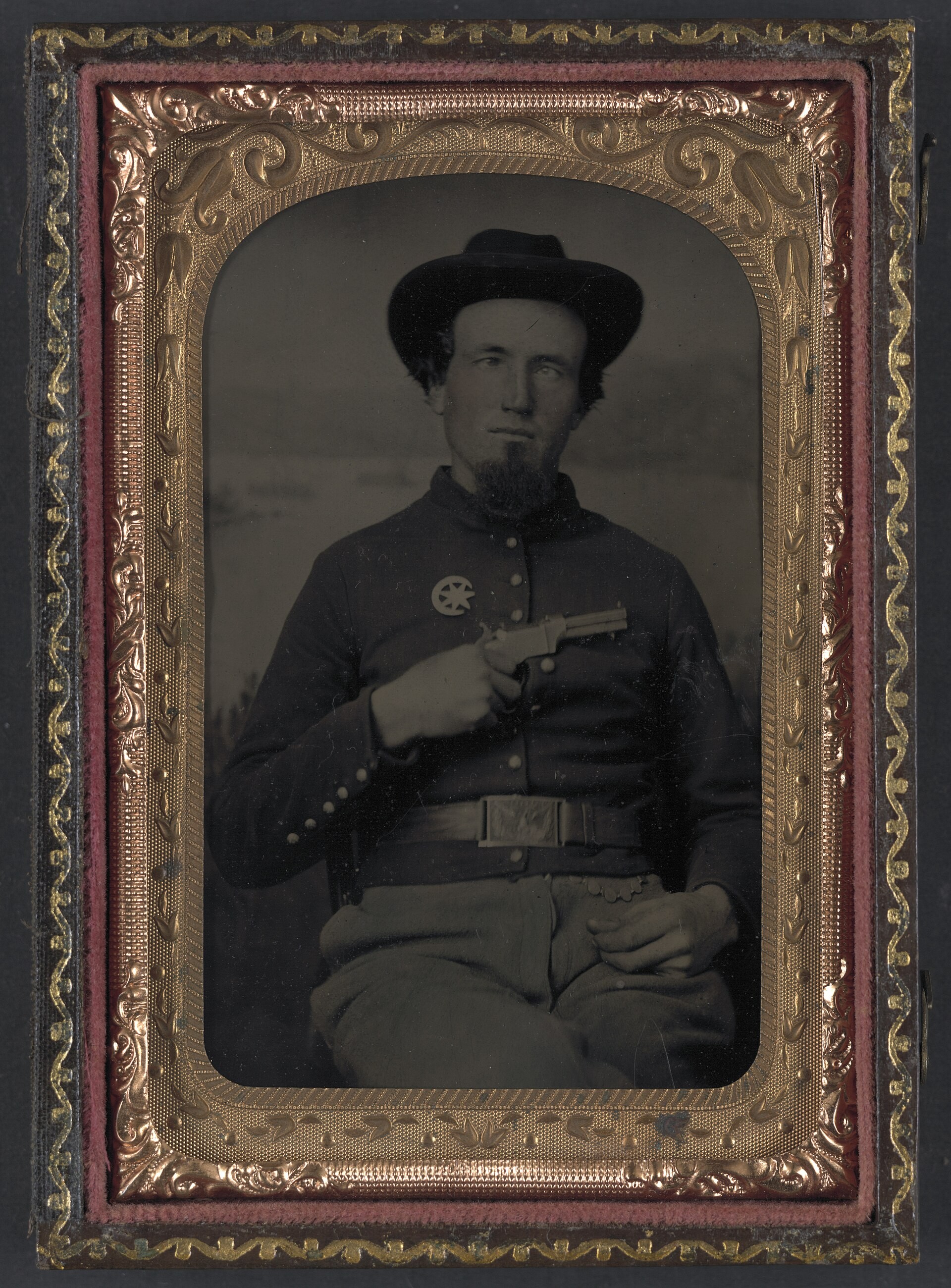 Figure 5 — An unidentified Union soldier holding a Volcanic-type pistol to his chest, tintype, 1861–1865. The 7th Corps, Department of Arkansas, insignia dates the photograph to the Civil War, after the Volca…