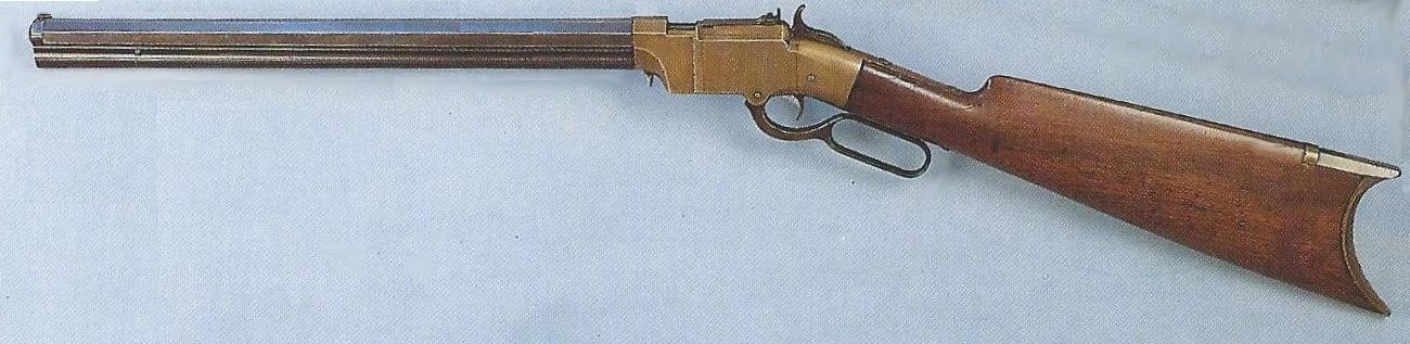 Figure 11 — A Volcanic carbine with a plain brass frame, left side; the barrel length is not stated by the source. The photograph appears to be scanned from a printed publication (a halftone screen shows under…