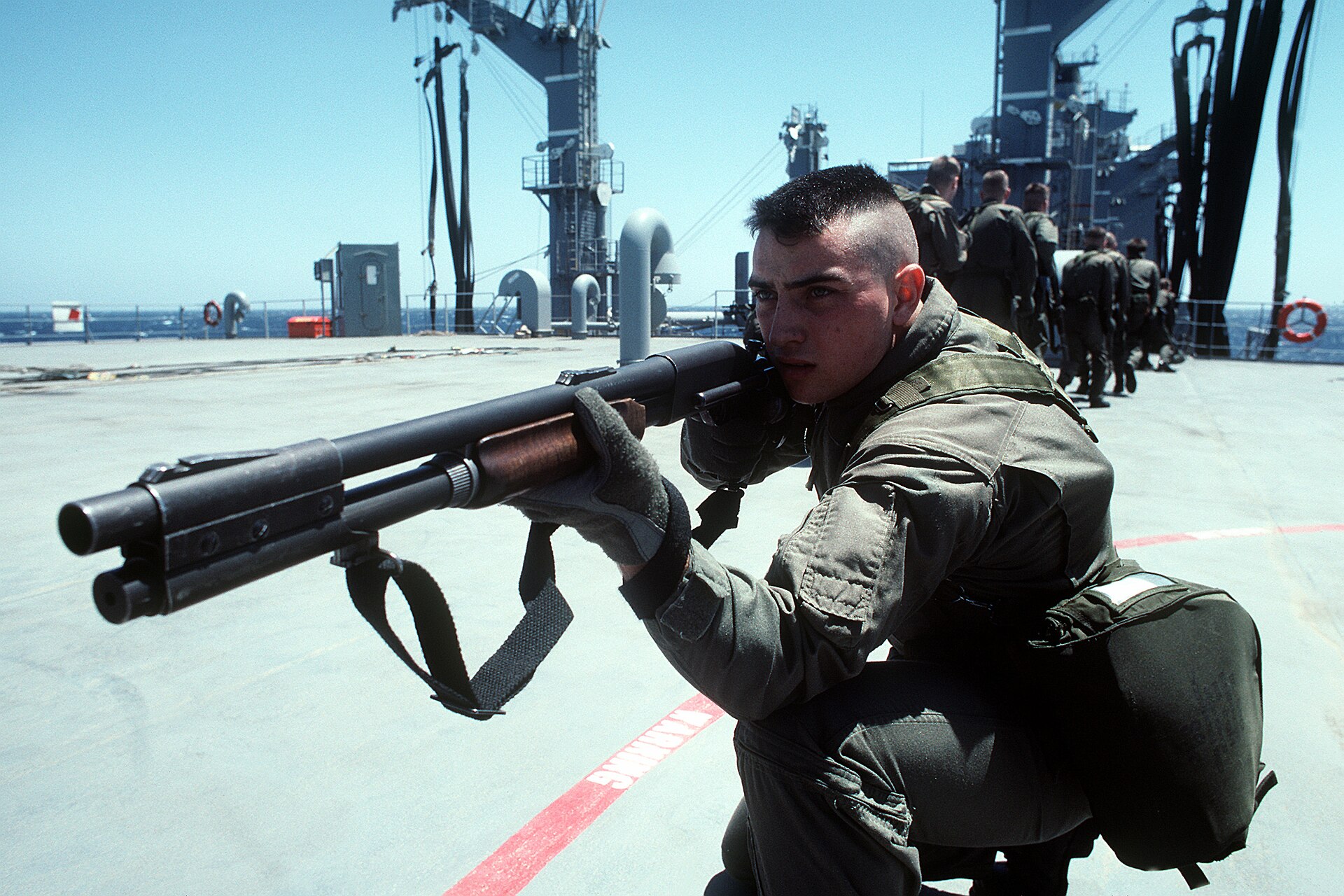 Figure 3 — A Marine from the USS Theodore Roosevelt's detachment aims an M870 during boarding-team training with SEAL Team 8 in March 1991, during the enforcement of United Nations sanctions against Iraq. Shi…