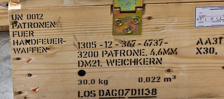 Figure 8 — The front of a crate stencilled "UN 0012 Patronen fuer Handfeuerwaffen" and "1305-12-367-6737 — 3200 Patrone, 4.6mm DM21, Weichkern", with its gross weight (30.0 kg), volume and lot number. DM21 is…