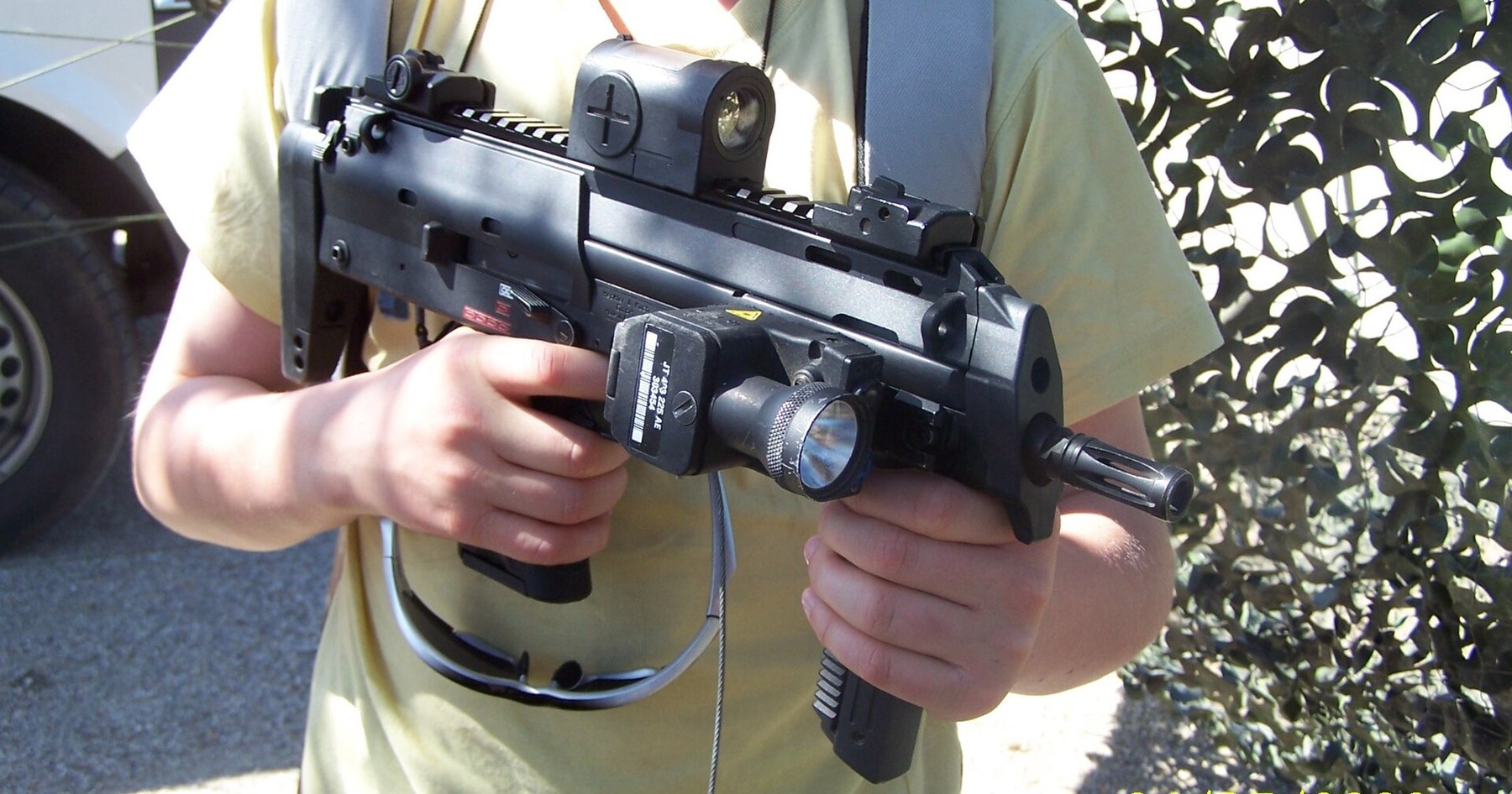 Figure 3 — An MP7 at a Bundeswehr display with a laser-light module on the right-side rail and its pressure-switch cable looped back towards the grip, and a reflex sight on the top rail. The stock is retracted.