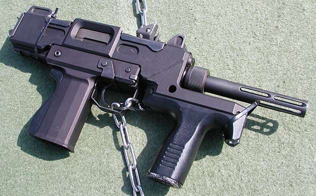 Figure 4 — An M9 from the right. The receiver's ejection opening is on this side, and the grip frame's metal is bare: Spear Head reports that the one-piece resin grip panel wraps only the rear and left of the…