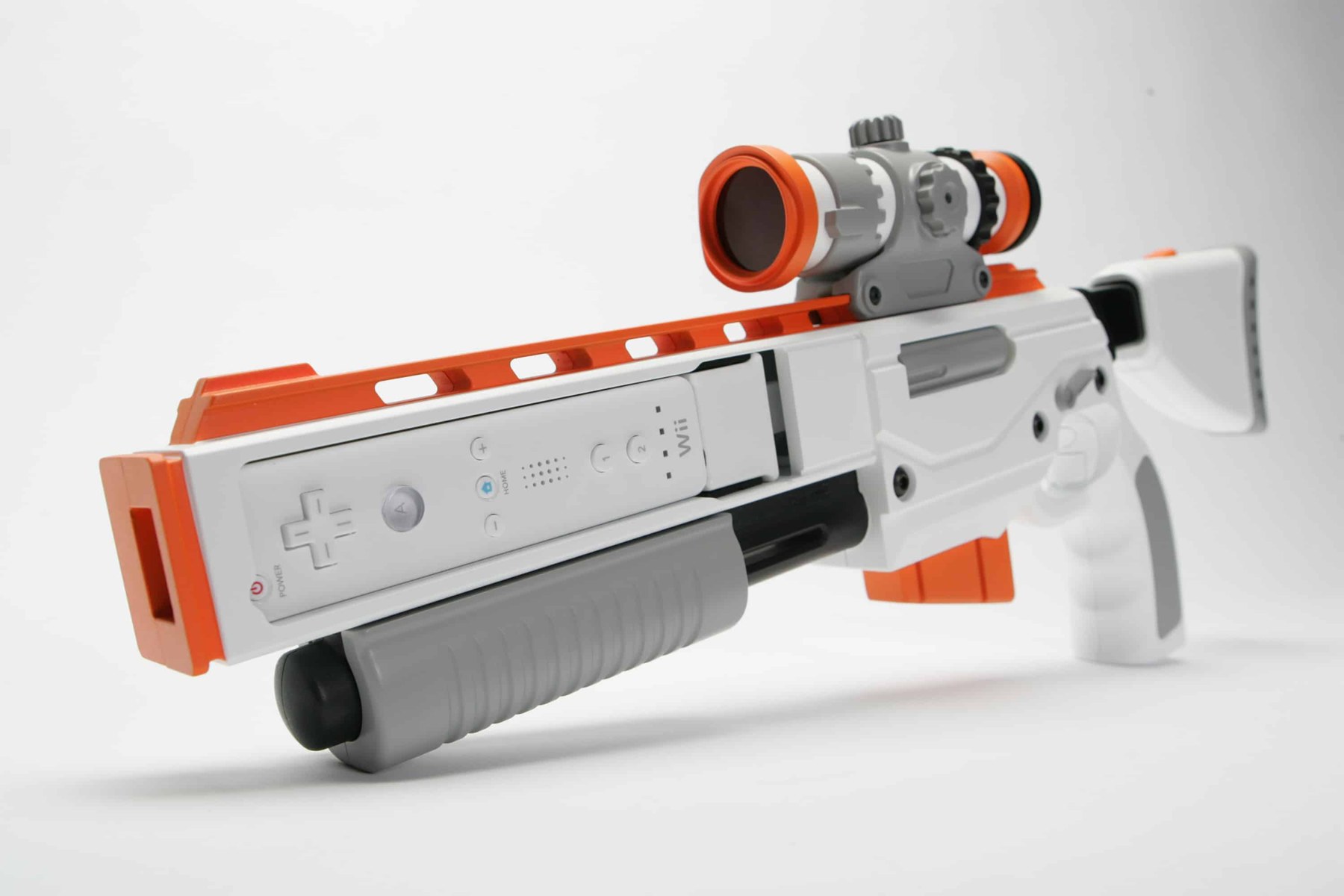 Figure 4 — The Activision Top Shot for the Wii: a white and orange rifle with a red-lens scope, a pump-action fore-end and an adjustable stock, holding a Wii Remote in the side of the receiver. It was designe…