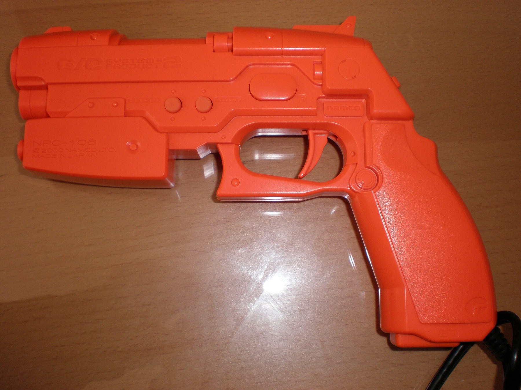 Figure 6 — An orange GunCon 2, packaged according to its photographer with Time Crisis 3. The mould is the same as the black gun's; the colour is the market's. Photo: BrokenSphere, Wikimedia Commons, CC BY-SA…
