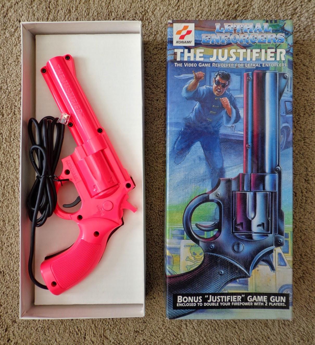 Figure 9 — A pink player-2 Justifier with its box, which calls it a "bonus Justifier game gun" and carries no console branding, consistent with its working with either console's blue gun. Photo: PriceCharting…