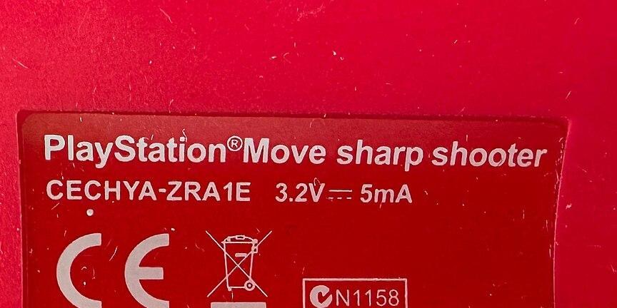 Figure 7 — The Sharp Shooter's label, inside the Move controller's compartment: "PlayStation Move sharp shooter, CECHYA-ZRA1E, 3.2 V, 5 mA", with CE, waste-electrical and Australian compliance marks and Sony …