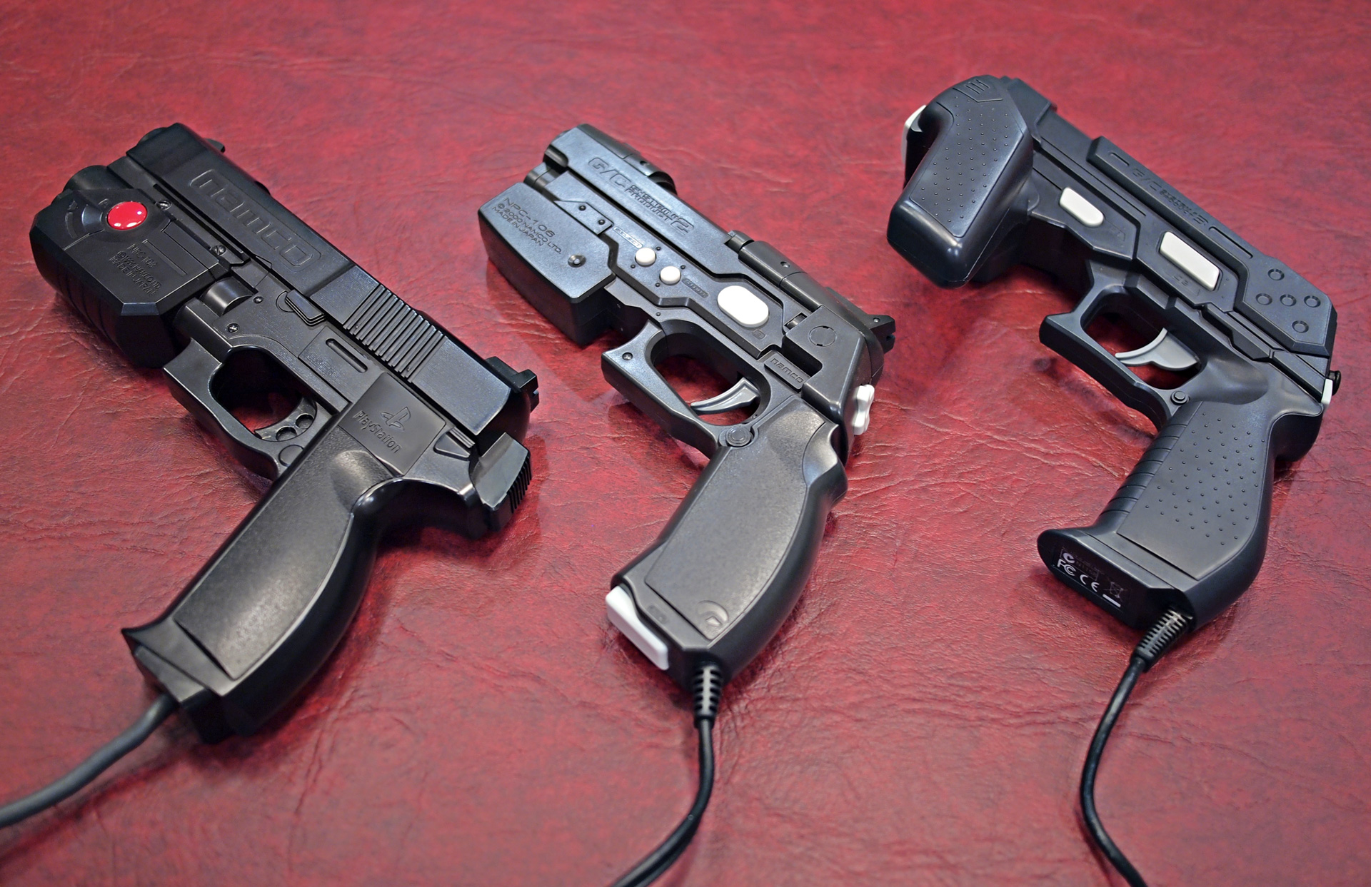 Figure 1 — Three generations of Namco's home gun. Left, the original GunCon for the PlayStation, which took its timing from the console's composite video. Centre, the GunCon 2 (NPC-106 on the slide) for the P…
