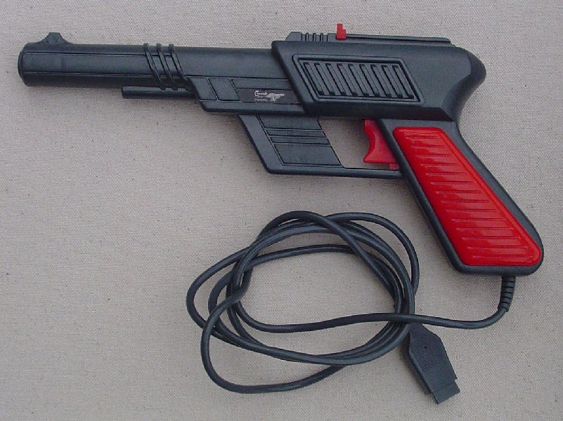 Figure 1 — The Cheetah Defender light gun in its Commodore 64 version, dark grey with red grips, with its cable ending in a 9-pin plug for the C64's control port. Photo: Spectrum Computing hardware archive.