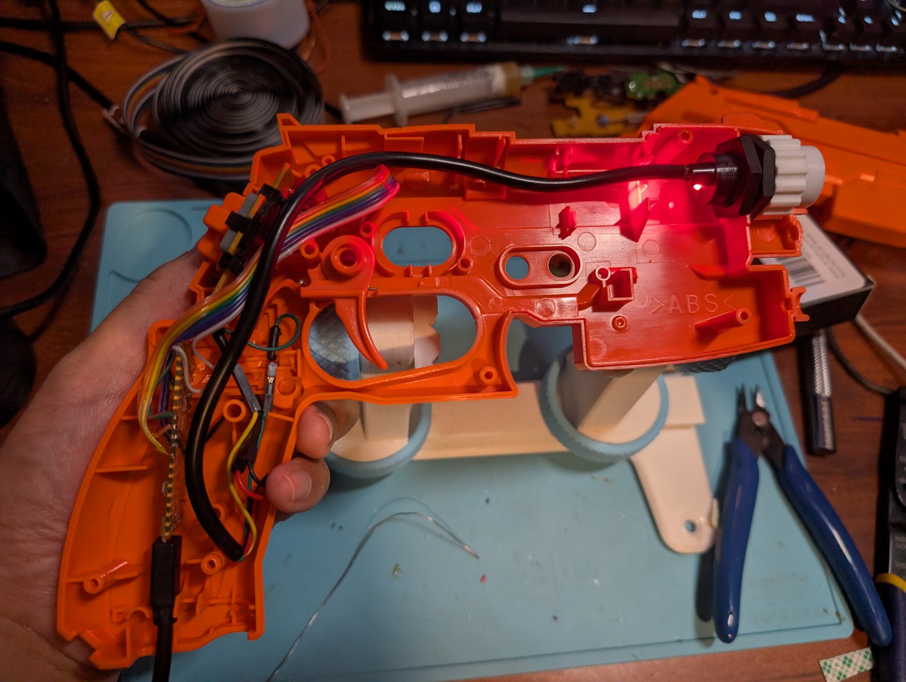 Figure 4 — A GunCon 2 converted with no carrier board: the IR camera in a printed coupler at the muzzle, the original main board kept along the slide, and a Pico-footprint board wired into the grip. Photo: Th…