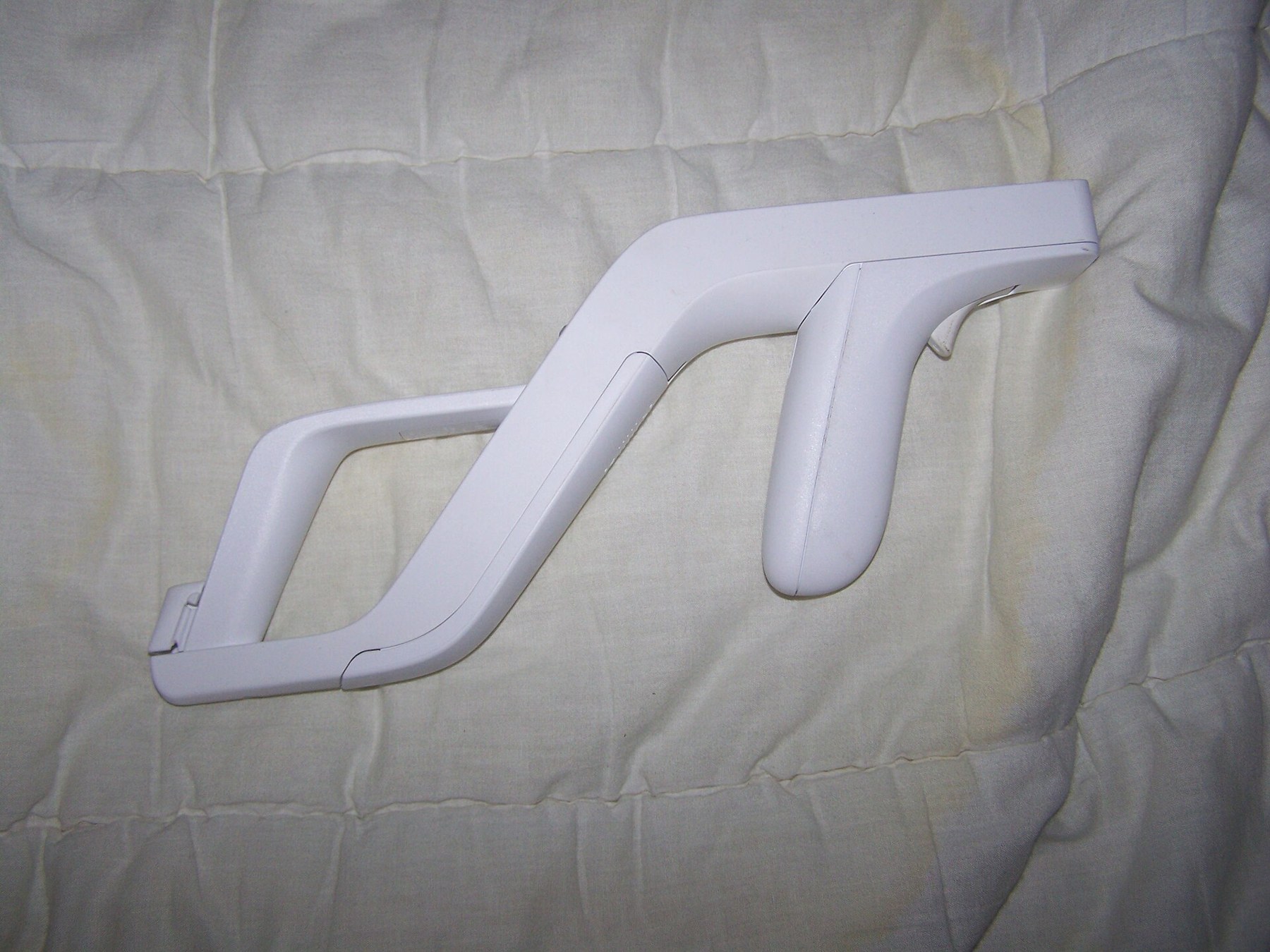 Figure 5 — The Wii Zapper empty: an open frame with a cradle at the front for the Wii Remote and a rear grip for the Nunchuk, and a trigger that presses the Remote's B button through a lever. Photo: Gabilolo,…