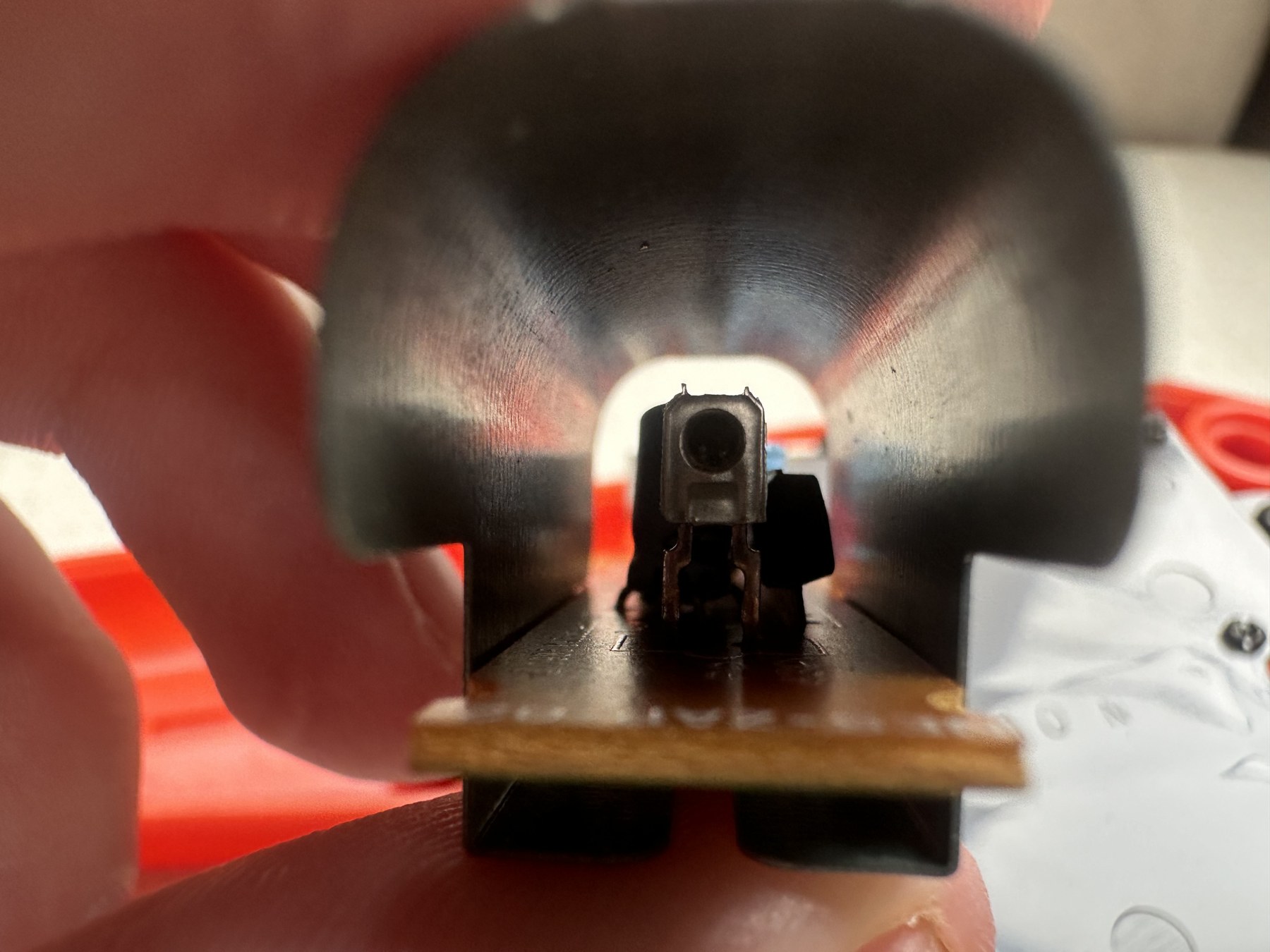 Figure 4 — The Zapper's photodiode seen down the barrel: the sensor sits behind a formed sheet-metal hood on a small board. The hood blocks stray light inside the gun and makes probing the board awkward. Phot…