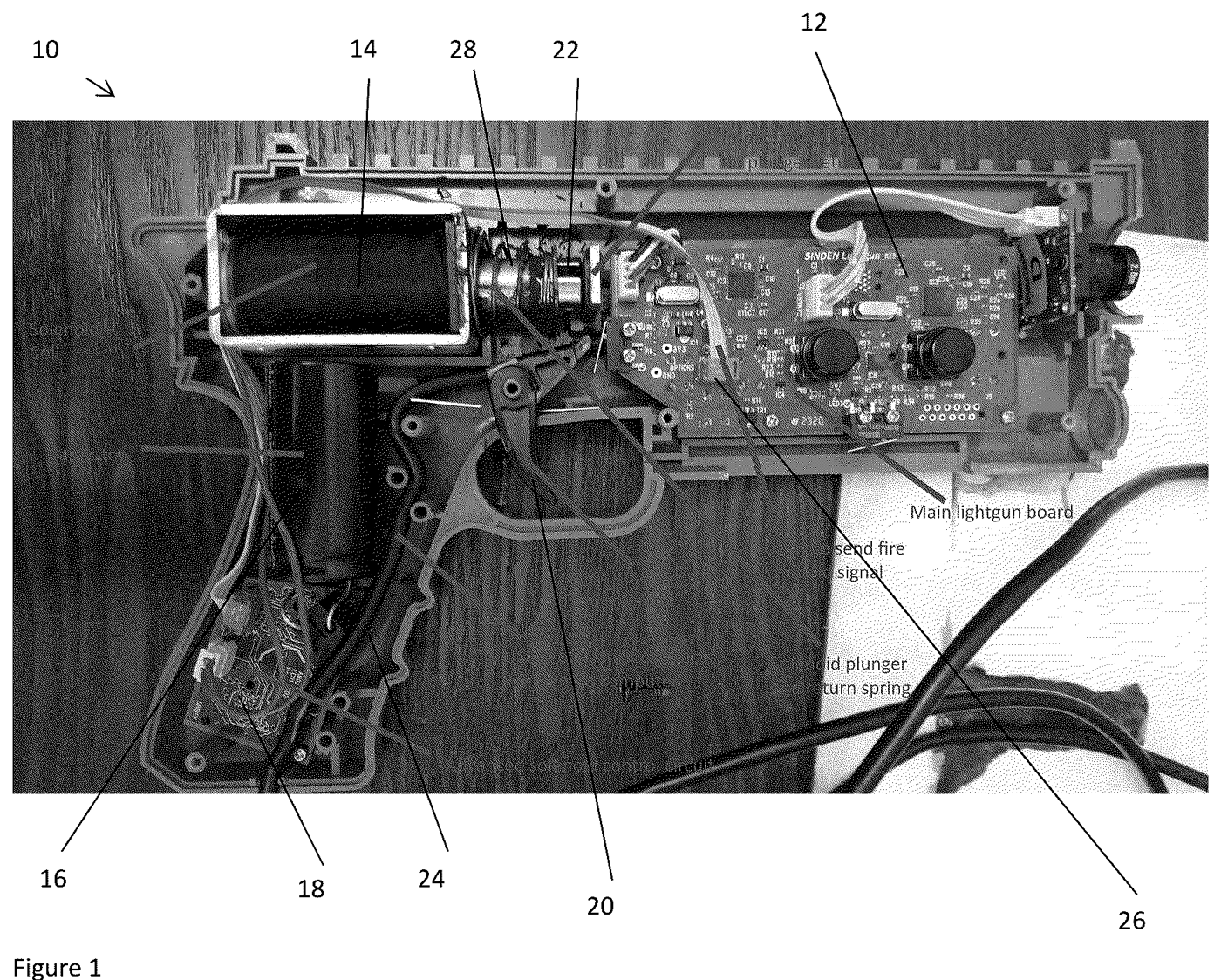 Figure 2 — Figure 1 of US 12,005,347: a photograph of a light gun's left shell half opened, with numbered parts. The solenoid coil (14) and its plunger and return spring sit at the top rear of the receiver; a…