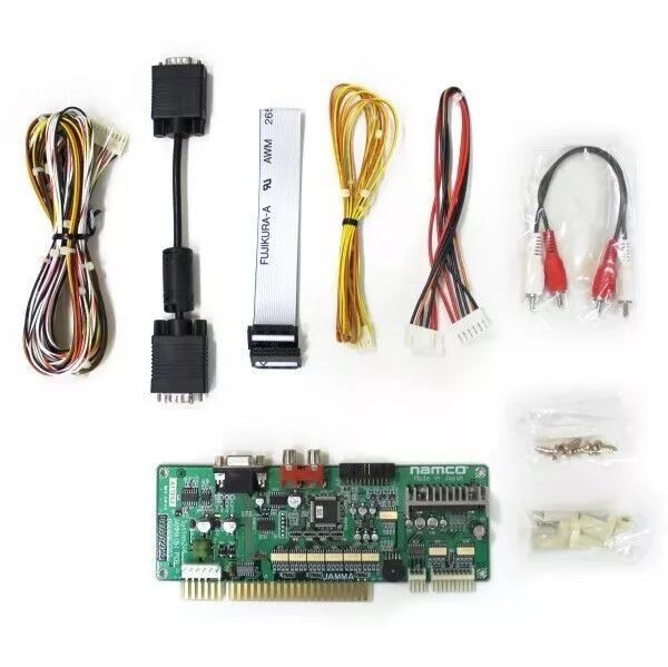Figure 2 — A Namco I/O PCB kit with its cables: a JAMMA edge-connector I/O board, harnesses, a VGA lead, a ribbon and RCA audio leads. Kits of this kind let a JVS-era Namco board sit in a JAMMA cabinet. Photo…