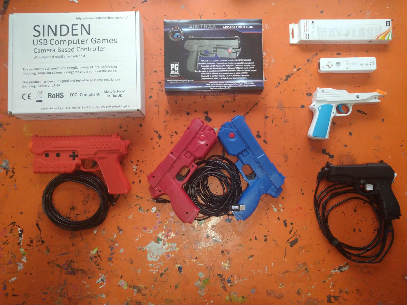 Figure 2 — The four light-gun systems one ARPiCADE forum member tested on a Raspberry Pi 4 in 2021: a Sinden (left, with its box), two AimTraks (centre), a Wii Remote in a gun shell with a Mayflash DolphinBar…