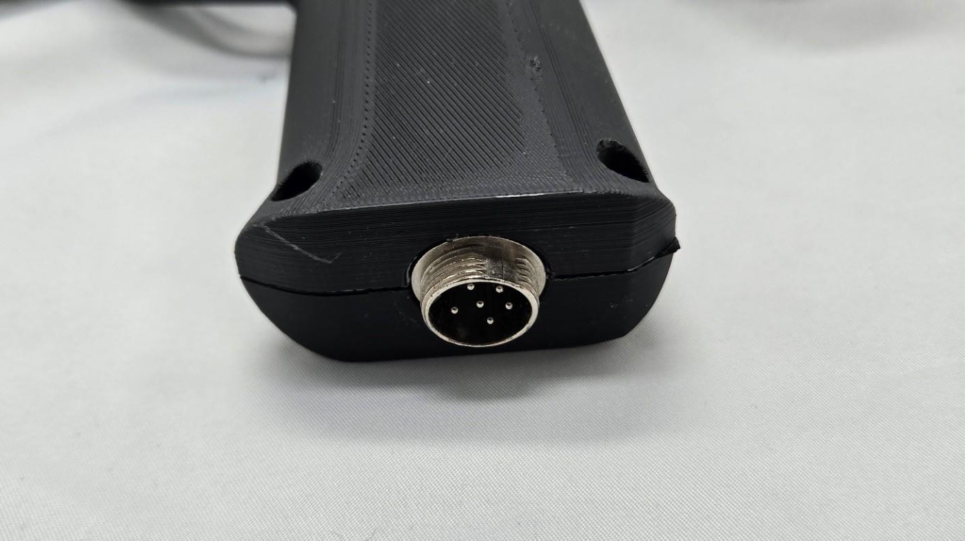 Figure 3 — The base of a Blamcon printed light gun's grip with its panel-mount GX16 connector, here a six-pin insert with five pins round a centre pin. One cable plugs in here and splits at its far end into U…