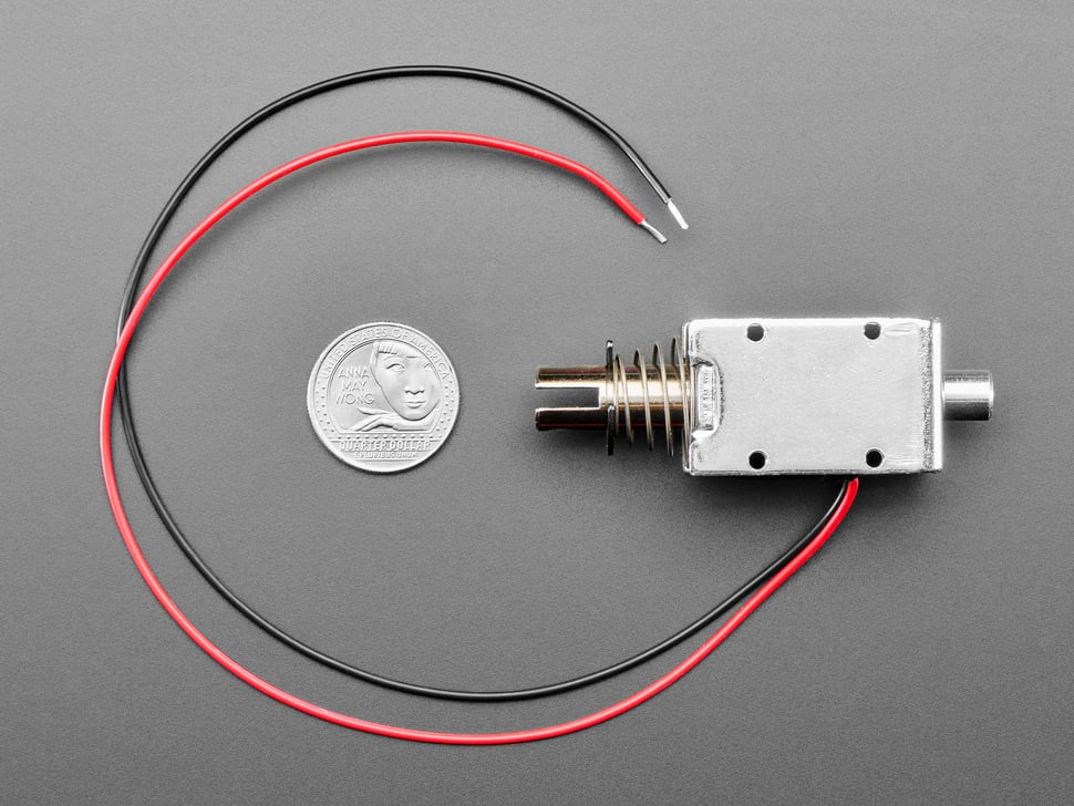 Figure 2 — Adafruit's large push-pull solenoid (product 413), the kind of open-frame coil many DIY recoil builds start with, shown with a US quarter for scale. Adafruit rates it for 12 V with a coil resistanc…