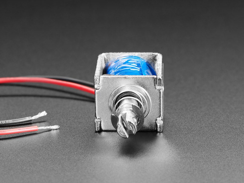Figure 2 — Adafruit's Medium Push-Pull Solenoid, product 3992, viewed from the push end: a box frame of folded steel around a coil wrapped in blue tape, the plunger's push end with its slot and cross-hole, an…