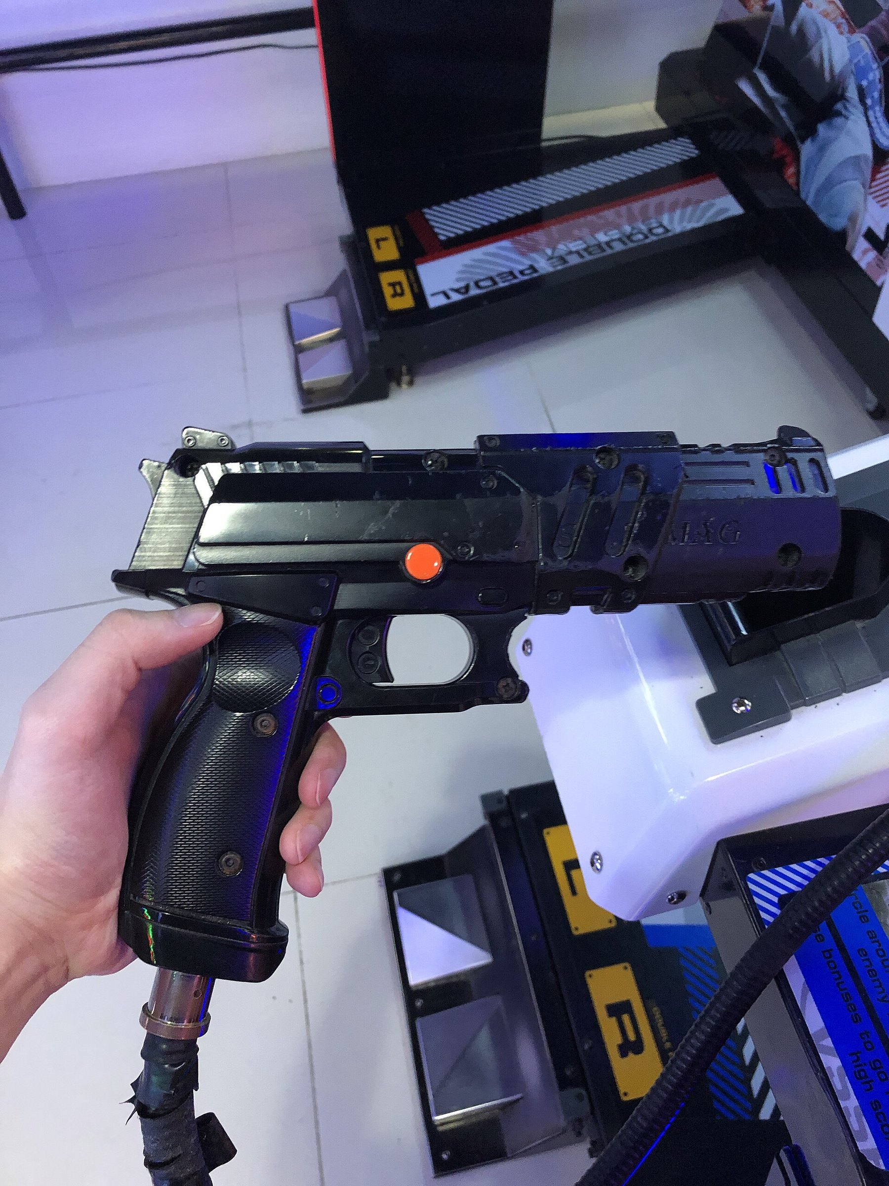 Figure 8 — A Time Crisis 5 gun in a player's hand. The later guns keep the separate upper slide; the solenoid that drives it is inside the receiver. Photo: Ominae, CC BY-SA 4.0, via Wikimedia Commons.