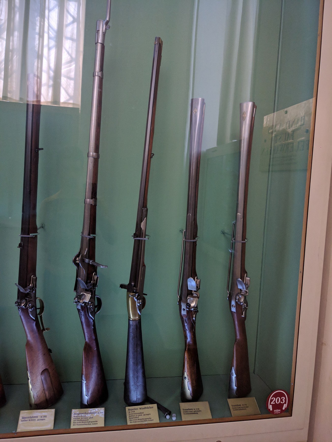 Figure 1 — Austrian military long arms in the Heeresgeschichtliches Museum, Vienna, with the Girandoni air rifle among them, its dark iron butt flask distinct from the wooden stocks of the flintlocks beside i…