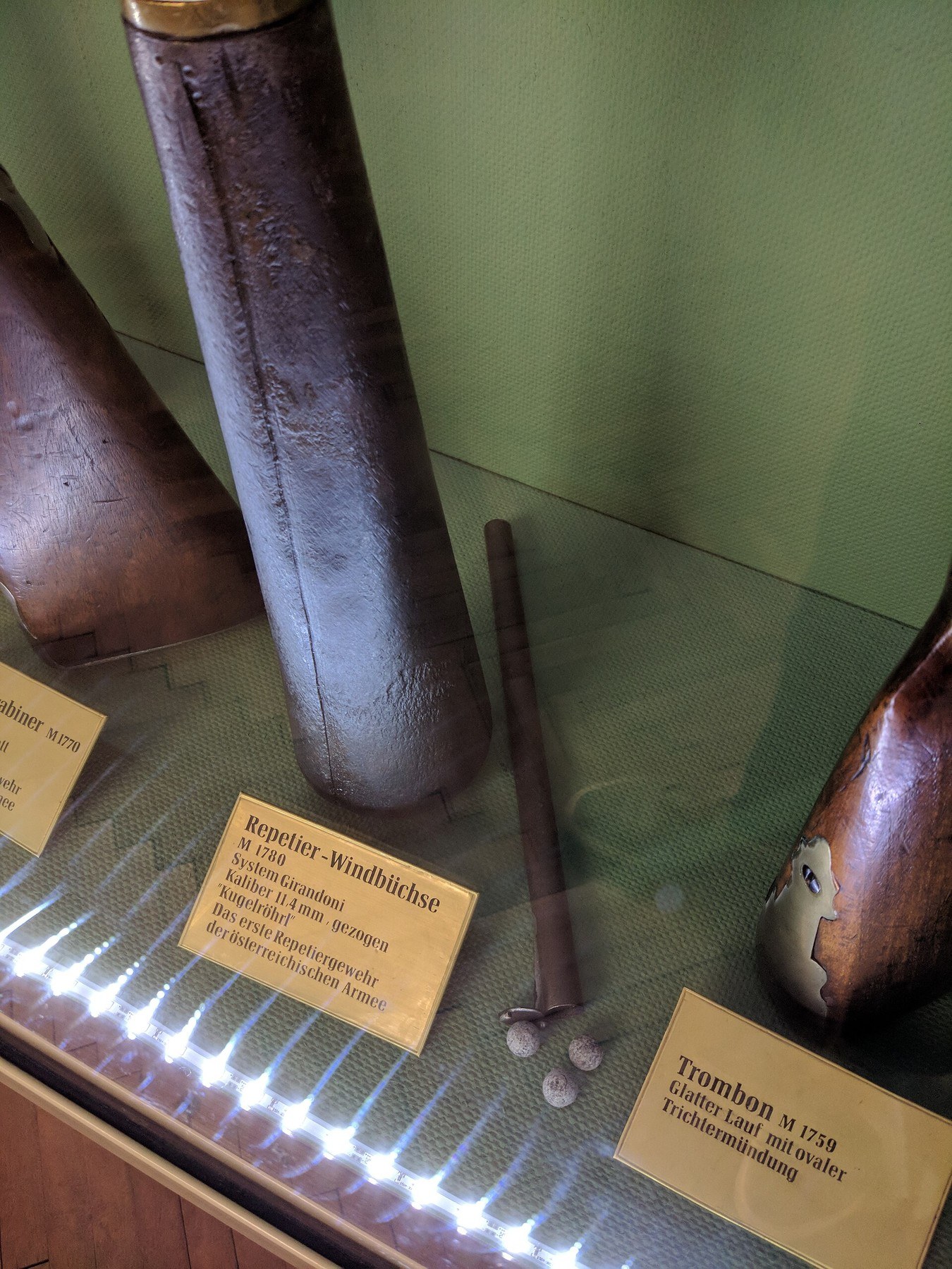 Figure 1 — The iron butt flask of a Girandoni air rifle in the Heeresgeschichtliches Museum, Vienna, with its brass collar at the top and the museum's label beside it. The label gives the calibre as 11.4 mm. …