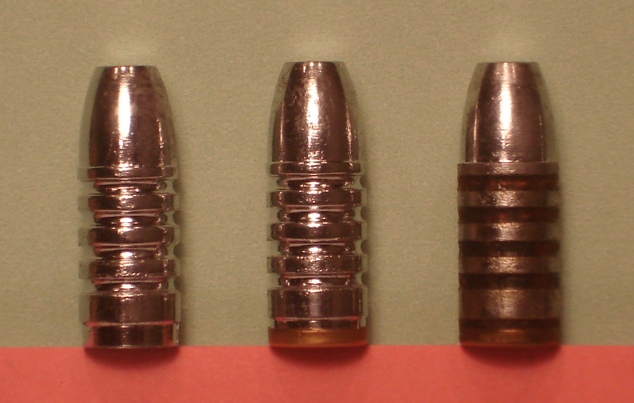 Figure 8 — Cast bullets at three stages: as cast, with a gas check fitted, and lubricated. Photograph by Thewellman, released CC0, via Wikimedia Commons (File:3CastBullets.png).